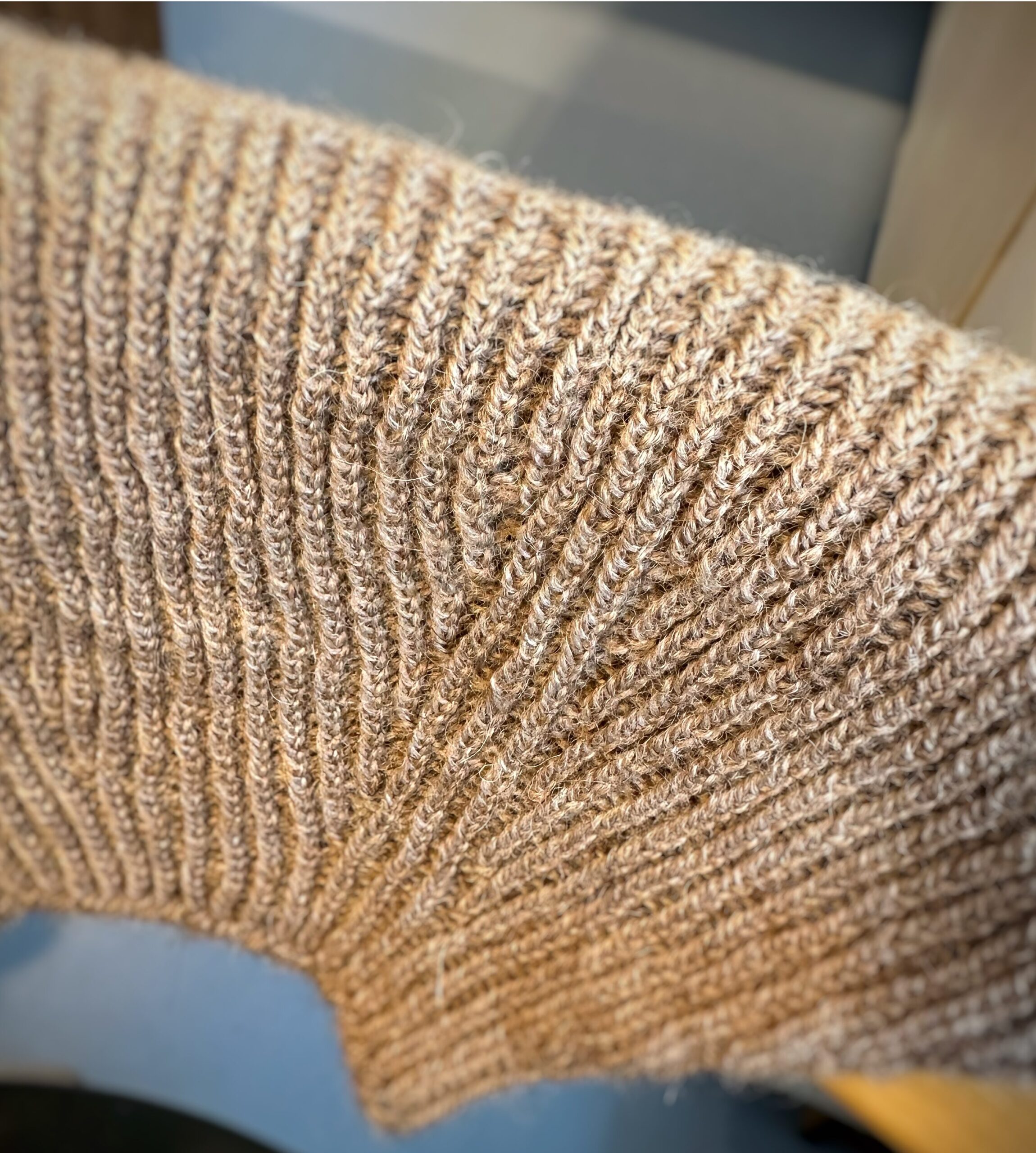 handknitted brown baby sweater on a stoolback